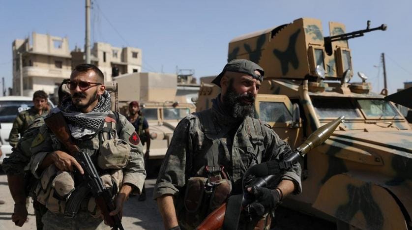 a_fighter_of_the_syrian_democratic_forces_sdf_carries_a_weapon_as_he_stands_near_a_military_vehicle_in_raqqa_syria._reuters.jpg